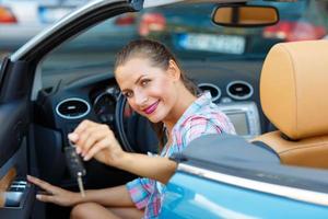 joven bonito mujer sentado en un convertible coche con el llaves en mano foto