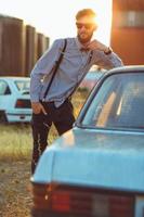 Young handsome stylish man, wearing shirt and bow-tie with old cars photo
