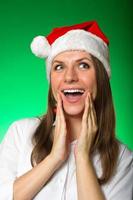 Girl in a Christmas hat on a green background photo