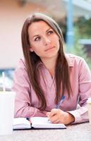 Businesswoman sitting in a cafe and writing in notepad photo