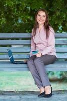 Businesswoman with computer laptop and credit card on the bench in the park photo