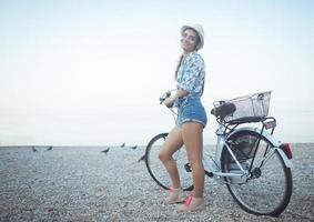 contento mujer con bicicleta en el playa foto