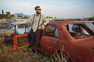 Young handsome stylish man, wearing shirt and bow-tie with old cars photo