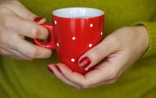 Woman hands holding a cozy red mug photo