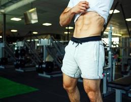 atlético hombre demostración abdominal músculos en gimnasio foto