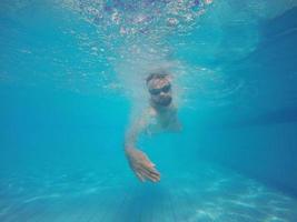 barba hombre con lentes nadando debajo agua en el piscina foto