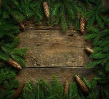 Christmas tree branches with cones on wooden texture ready for your design photo