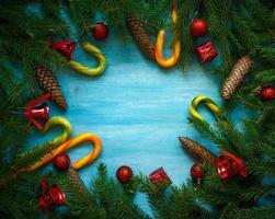 Christmas border with fir tree branches, cones, christmas decorations and candy cane on blue wooden boards photo