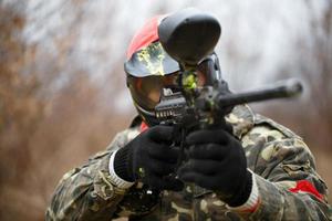 Paintball sport player wearing protective mask and aiming gun photo