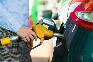mujer llena gasolina dentro el coche a un gas estación foto