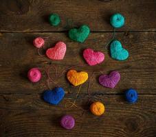 Multicolored Hearts with a balls of thread on old shabby wooden background photo