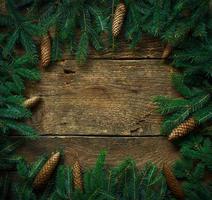 Christmas tree branches with cones on wooden texture ready for your design photo