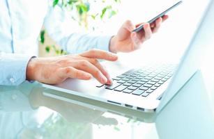 Men office worker typing on the keyboard and using smartphone photo