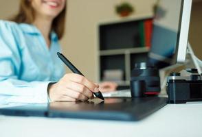 Young artist drawing something on graphic tablet at the home office photo