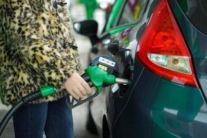 mujer llena gasolina dentro su coche a un gas estación en invierno foto