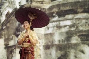 asiático mujer participación bambú paraguas en pie en antiguo templo a ayutthaya mundo patrimonio sitio de la unesco Tailandia foto