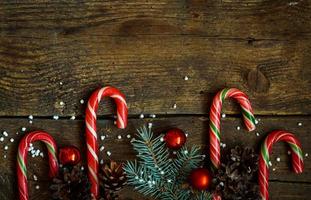 Christmas border with fir tree branches, cones, christmas decorations and candy cane on  wooden boards photo