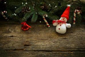 Christmas tree branches with christmas decorations and snowman on wooden texture photo