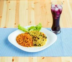 Dish made of two kinds of rice on a white plate and a glass of juice with ice photo