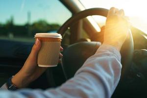 Woman with coffee to go driving her car photo