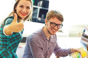 Beautiful young woman and man with thumb up in office photo