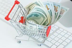 Dollars in the shopping cart on a computer keyboard photo