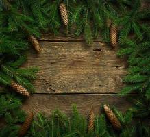 Christmas tree branches with cones on wooden texture ready for your design photo