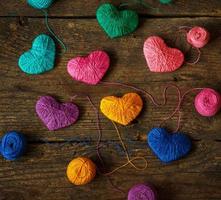 Multicolored Hearts with a balls of thread on old shabby wooden background photo