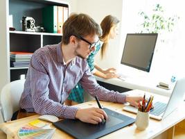 Young artist drawing something on graphic tablet at the office photo