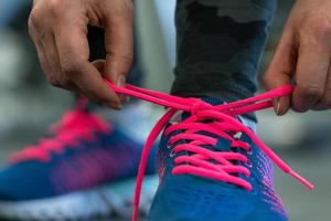 Running shoes - woman tying shoe laces. Woman getting ready for engage in the gym photo