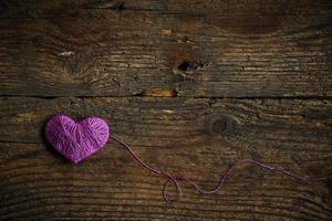 púrpura corazón con un pelota de hilo en en antiguo desgastado de madera antecedentes foto