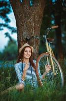 Lovely young woman in a hat with a bicycle outdoors photo