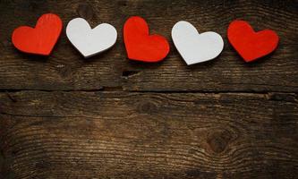 Red and white hearts on old wooden background photo