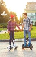 A young couple riding hoverboard - electrical scooter, personal eco transport, gyro scooter, smart balance wheel photo