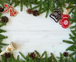 Christmas border with fir tree branches, cones and christmas decorations on white wooden boards photo