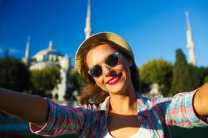 Girl in the hat making selfie by the smartphone on the background of the Blue Mosque, Istanbul photo