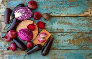 Collection of fresh purple vegetables on the blue wooden background