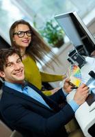 Young colleague looking to a color paint palette at home office photo