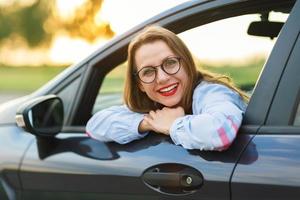 joven contento mujer sentado en un coche foto
