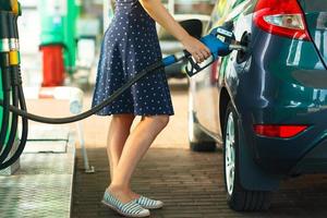 mujer llena gasolina dentro el coche a un gas estación foto