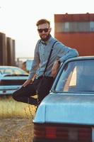 joven hermoso elegante hombre, vistiendo camisa y corbata de moño con antiguo carros foto