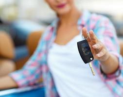 Woman standing near a convertible with keys in hand - concept of buying a used car or a rental car