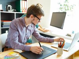 Artist drawing something on graphic tablet at the home office photo