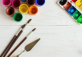 Watercolors and paint brush on white wooden background photo