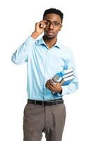 African american college student with books and bottle of water in his hands standing on white photo