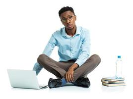africano americano Universidad estudiante con computadora portátil, libros y botella de agua sentado en blanco foto
