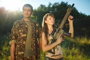 White girl and an Arab man in camouflage with a weapon in the hands of outdoors photo