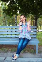 un retrato de un sonriente mujer en un parque en un banco hablando en el teléfono foto