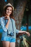 Lovely young woman in a hat with a bicycle outdoors photo