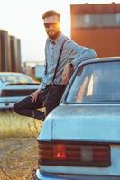 joven hermoso elegante hombre, vistiendo camisa y corbata de moño con antiguo carros foto